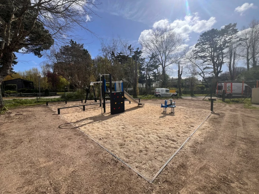 Aire de jeux extérieure avec pelouse en cours de repousse dans un camping